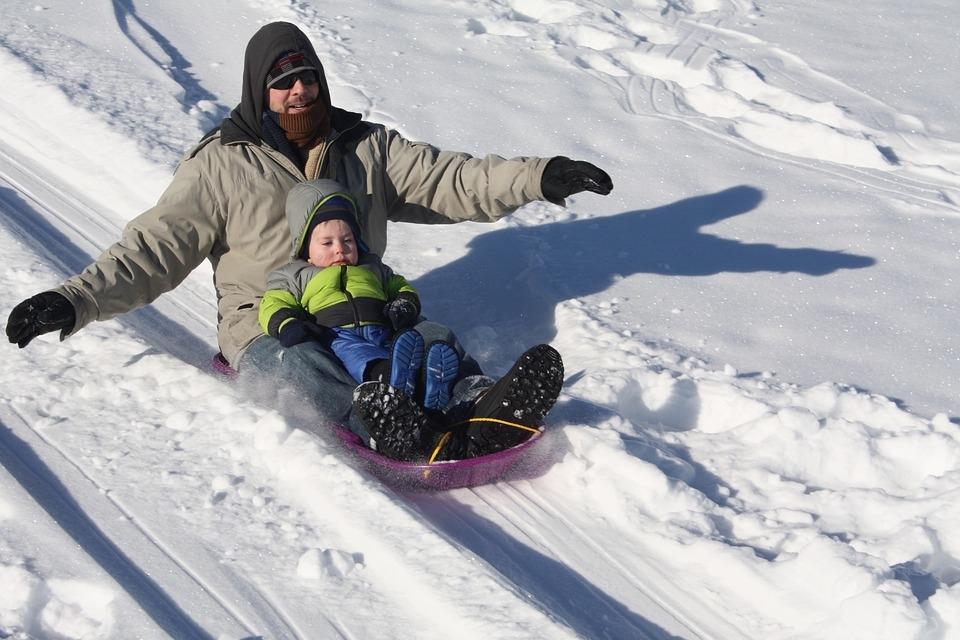 man sledding with child